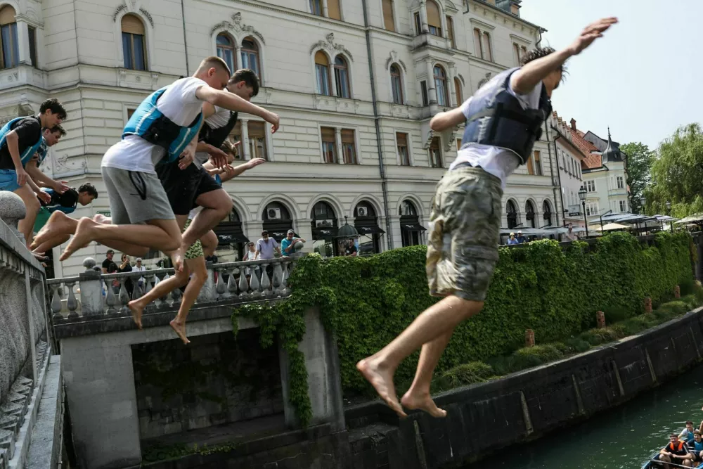 11.06.2025. Skupina mladeničev skače v Ljubljanico s Tromostovja. Vročinski val. Foto: Bojan Velikonja 