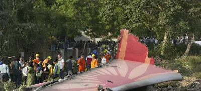 People stand around the debris of an airplane after it crashed in India's northwestern city of Ahmedabad in Gujarat state, Thursday, June 12, 2025. (AP Photo/Ajit Solanki)