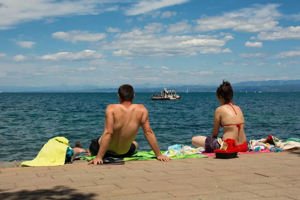 Izola, Slovenia - 9th July 2022. A couple watch a coast guard boat intercept a jet ski personal watercraft which was too speeding close to the shore. At Izola on Slovenia's Adriatic coast