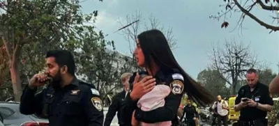 Policistka v rokah drži rešenega otroka.