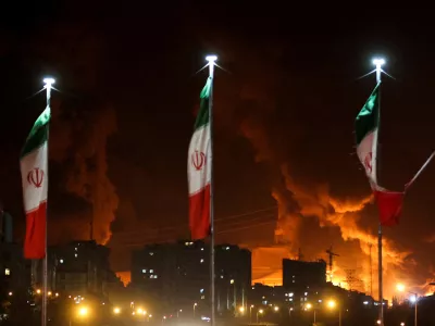 FILE PHOTO: Iranian flags fly as fire and smoke from an Israeli attack on Sharan Oil depot rise, following Israeli strikes on Iran, in Tehran, Iran, June 15, 2025. Majid Asgaripour/WANA (West Asia News Agency) via REUTERS  ATTENTION EDITORS - THIS PICTURE WAS PROVIDED BY A THIRD PARTY/File Photo / Foto: Majid Asgaripour