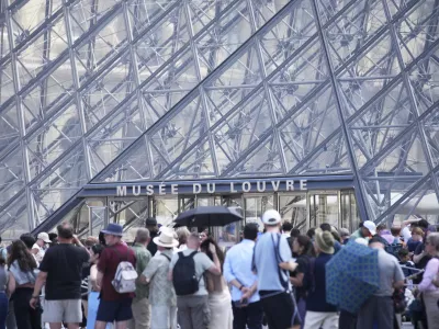 Tourists wait outside the Louvre museum which failed to open on time Monday, June 16, 2025 in Paris. (AP Photo/Christophe Ena)
