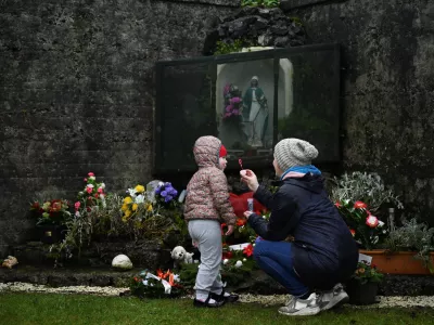 Denise Gormley and her daughter Rosa, 7, pay their respects and blow bubbles at the Tuam graveyard, where the bodies of 796 babies were uncovered at the site of a former Catholic home for unmarried mothers and their children, on the day a government-ordered inquiry into former Church-run homes for unmarried mothers is formally published, in Tuam, Ireland, January 12, 2021. REUTERS/Clodagh Kilcoyne