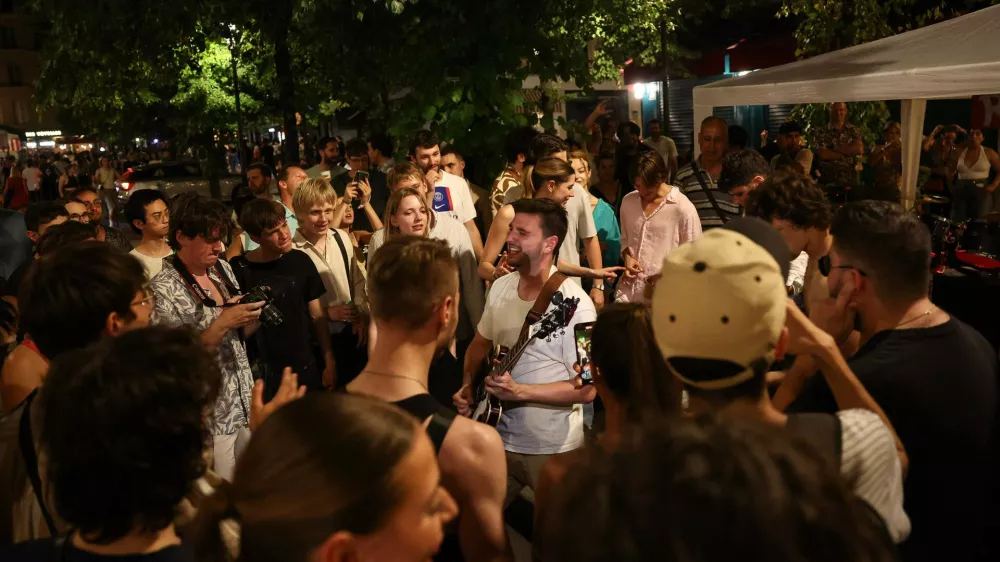 21 June 2025, France, Paris: Music enthusiasts listen to a man playing the guitar during the annual French street music festival "Fete de la Musique" in the 4th arrondissement of Paris. Photo: Romain Perrocheau/AFP/dpa