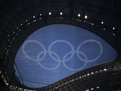 The Olympic rings are pictured through a flag hanging in the Velodrome stadium before the start of the men's Group A soccer match between France and the United States during the 2024 Summer Olympics, Wednesday, July 24, 2024, in Marseille, France. (AP Photo/Daniel Cole)