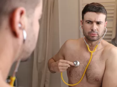 A cute man in his forties is listening to his own heartbeat. He is shirtless and looks gorgeous. / Foto: Ajr_images