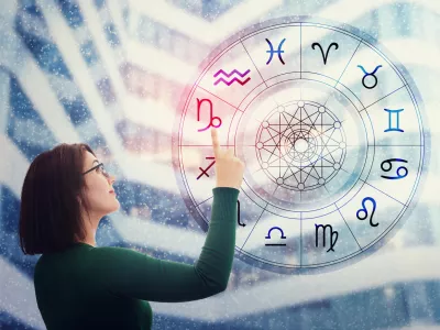 Woman choosing a zodiac sign from the astrological wheel to find the future predictions. Having trust in horoscope, consulting stars and believe in the power of universe. Astrology esoteric concept. / Foto: Bulat Silvia