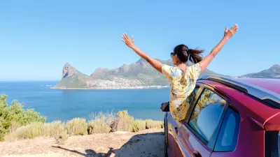woman outside a car window with hands up, a car at Chapmans Peak Drive in Cape Town South Africa looking out over the ocean. women on a road trip garden route South Africa with renal car / Foto: Fokkebok