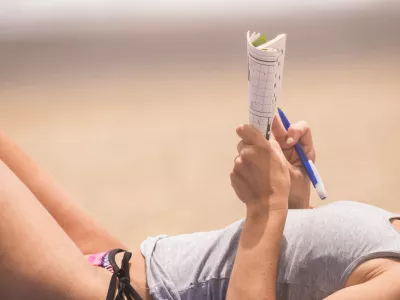 beautiful woman close up on body relaxed and have nice time doing a words play on paper. beach vacation leisure activity under the sunlight. skin tanner concept in holiday outdoor activity for lady / Foto: Simonapilolla