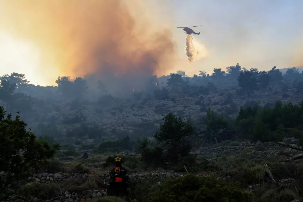 A firefighting helicopter drops water to extinguish fire at the area of Kontylopos on Chios island, Greece, June 24, 2025. REUTERS/Kostas Anagnostou   TPX IMAGES OF THE DAY
