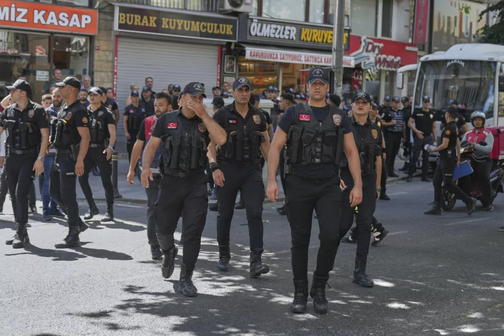 Turkish police officers walk as people gather and celebrate the annual LGBTQ+ Pride March, in Istanbul, Turkey, Sunday, June 29, 2025. (AP Photo/Dilara Acikgoz)