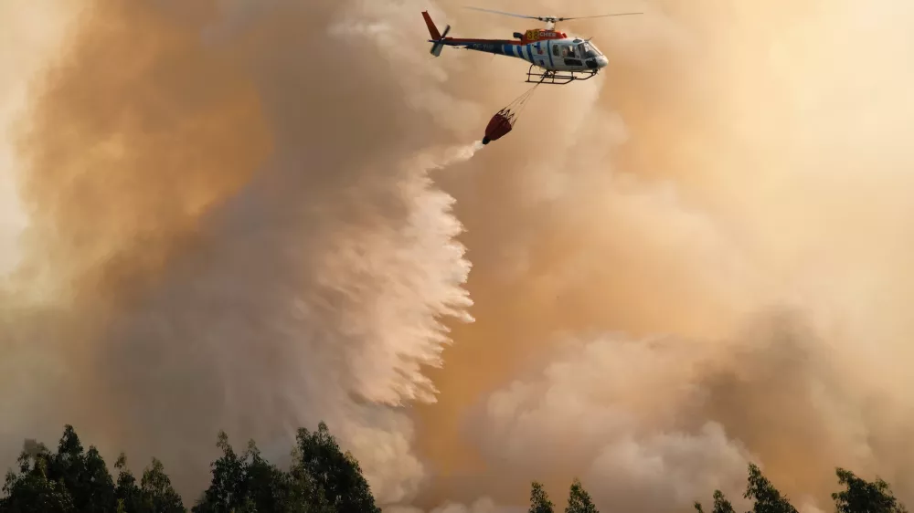 A firefighting helicopter drops its load of water on a forest fire near Santa Comba Dao, northern Portugal, Thursday, Aug. 11 2016. Firefighters in Portugal are battling multiple blazes fed by brush in a hot, dry summer for a sixth straight day. Major fires have also been raging in northwestern Spain and southern France. (AP Photo/Sergio Azenha)