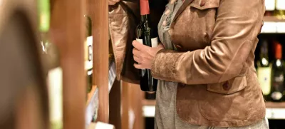 shoplifting - a woman steals a bottle of wine in a supermarket / Foto: Industryview