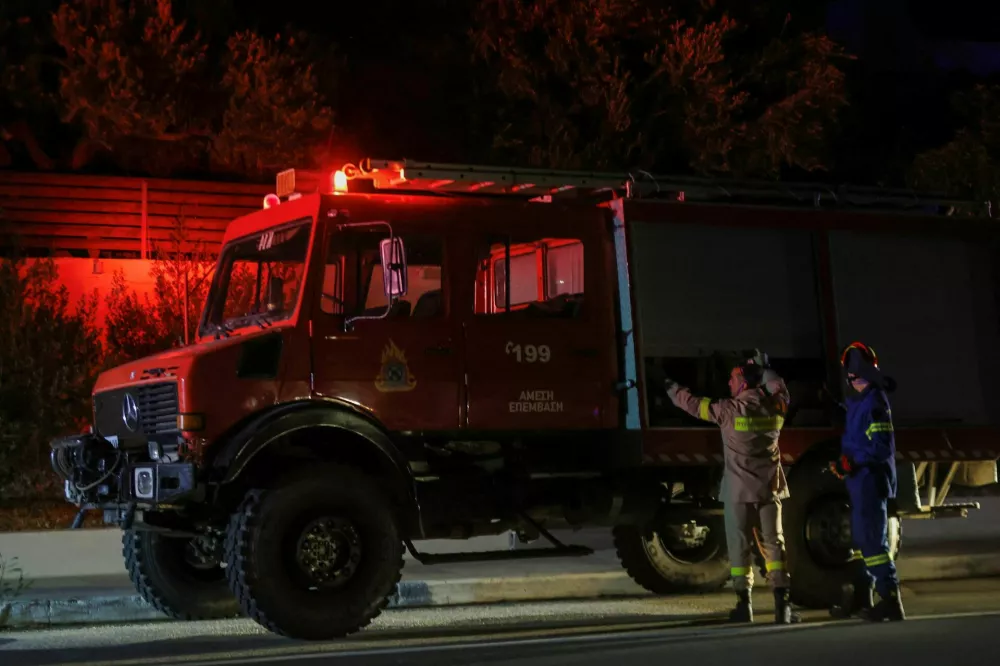 Firefighters stand next to a vehicle as a wildfire burns near Ierapetra, on the island of Crete, Greece, July 2, 2025. REUTERS/Stefanos Rapanis