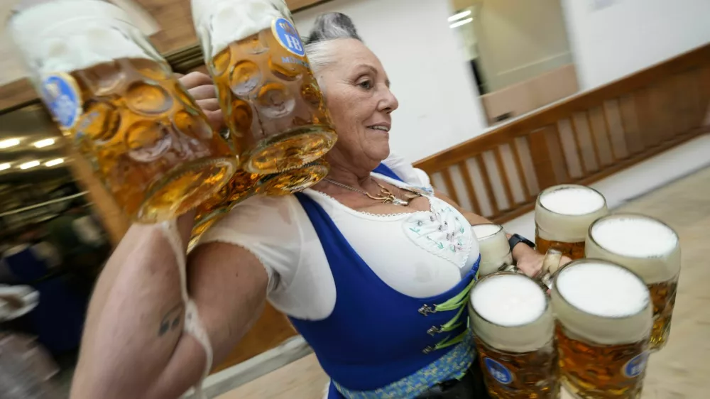 A waitress carryies beer mugs in the Hofbraeuhaus beer tent, on day one of the 189th 'Oktoberfest' beer festival in Munich, Germany, Saturday, Sept. 21, 2024. (AP Photo/Matthias Schrader)