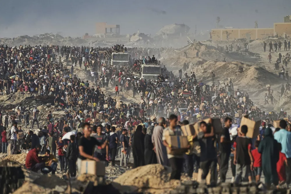Palestinians carry sacks and boxes of food and humanitarian aid, unloaded from a World Food Program convoy that was heading to Gaza City in the northern Gaza Strip, Monday, June 16, 2025. (AP Photo/Jehad Alshrafi)