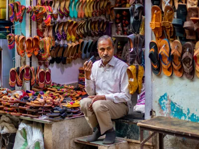 nathdwara, India &ndash; February 21, 2021: A shopkeeper sitting outside at his Juttis & Mojaris shop listening to something on the phone