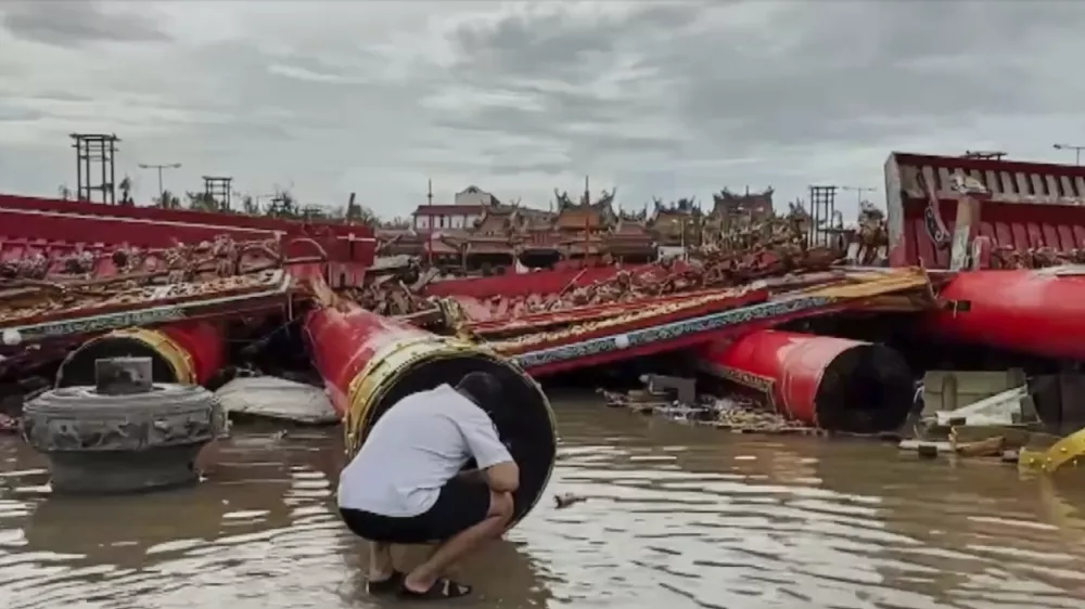 In this image made from a video provided by TVBS, a resident checks the collapsed temple structures submerged in floodwaters Monday, July 7, 2025, after the Typhoon Danas landed in Tainan, Taiwan. (TVBS via AP)