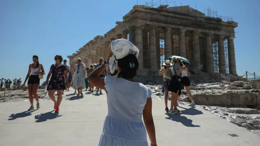 A woman protects her head from the sun, while visiting the Acropolis, at the start of a 3-days heatwave with temperatures expected to overpass 40 Celsius degrees, in Athens, Greece, July 7, 2025. REUTERS/Louisa Gouliamaki
