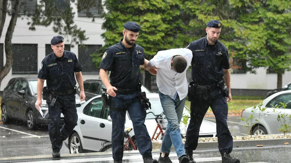 Emanuel Rep v spremstvu policistov na zasli&scaron;anje v Varaždinu. Sumijo ga umora mame s sekiro ter poskusa umorov polbrata in očima. 