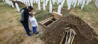 Aljo Mujcic, a Bosnian man, shows his sons a spot dug ahead of a mass funeral marking the 30th anniversary of the Srebrenica genocide, at the Srebrenica-Potocari Memorial Center in Potocari, near Srebrenica, Bosnia and Herzegovina, July 10, 2025. REUTERS/Amel Emric