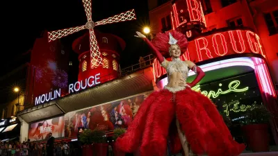 A French Cancan dancer poses in front of the Moulin Rouge cabaret during celebrations marking the restart of its iconic windmill with red sails, in Paris, France, July 10, 2025. REUTERS/Tom Nicholson
