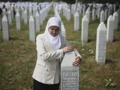 A woman holds a gravestone at the Memorial Center in Potocari, Bosnia, Friday, July 11, 2025. (AP Photo/Armin Durgut)