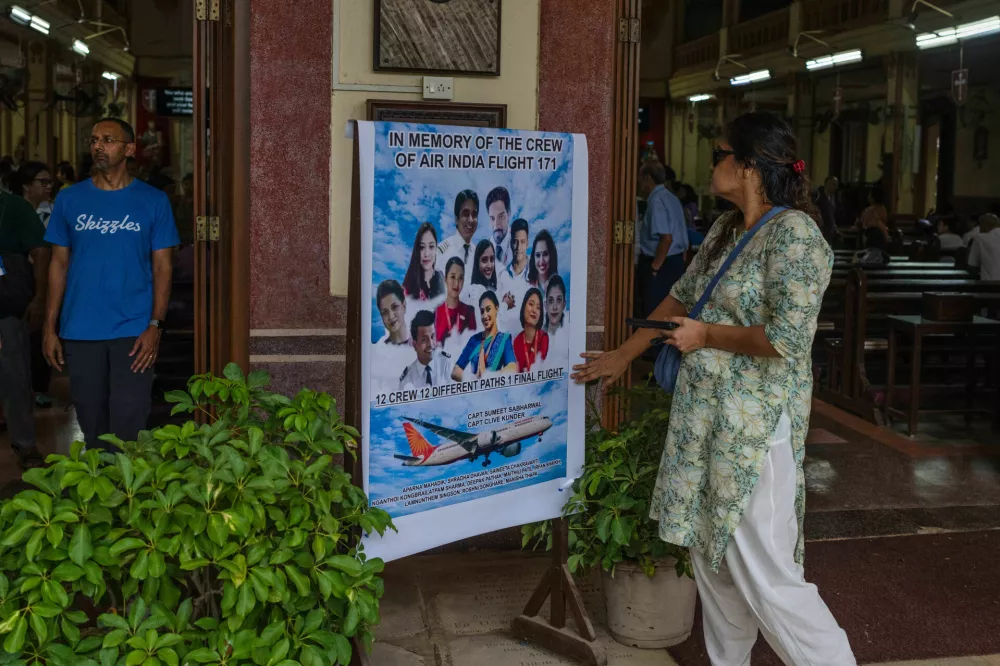 A woman offers tribute to the crew members of the Air India flight that crashed in Ahmedabad last month during a prayer meeting at a church in Mumbai, India, Saturday, July 12, 2025. (AP Photo/ Rafiq Maqbool)