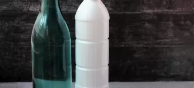 Glass milk bottle and plastic white bottle on grey background. Reusable packaging. The concept of environmental protection.Empty space for text. Selective focus.