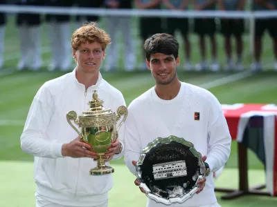 Tennis - Wimbledon - All England Lawn Tennis and Croquet Club, London, Britain - July 13, 2025 Italy's Jannik Sinner celebrates with the trophy after winning the men's final alongside runner up Spain's Carlos Alcaraz REUTERS/Toby Melville   TPX IMAGES OF THE DAY