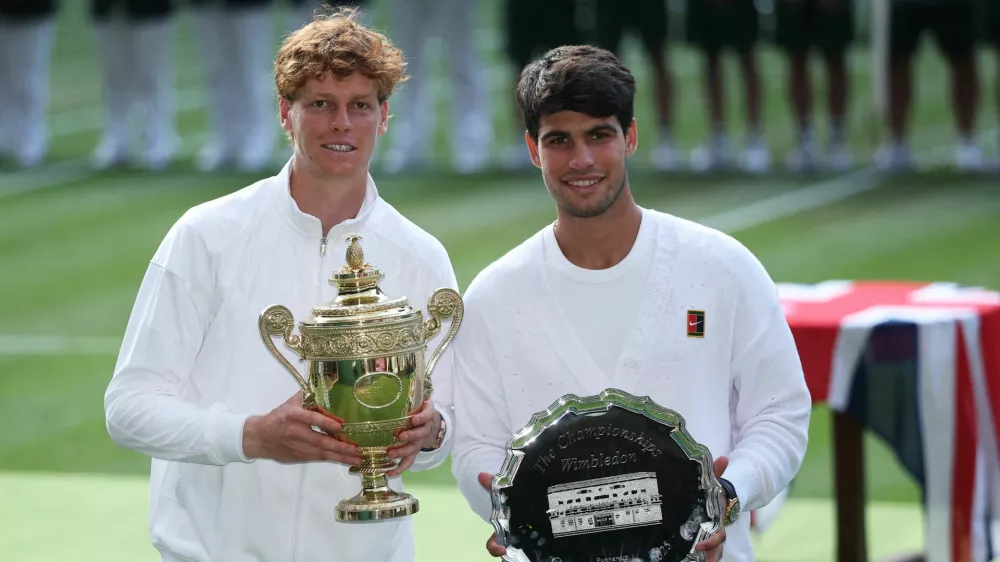 Tennis - Wimbledon - All England Lawn Tennis and Croquet Club, London, Britain - July 13, 2025 Italy's Jannik Sinner celebrates with the trophy after winning the men's final alongside runner up Spain's Carlos Alcaraz REUTERS/Toby Melville   TPX IMAGES OF THE DAY