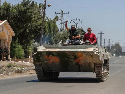 Syrian government forces sit on their armored personnel carrier, as they withdraw from Sweida city, southern Syria, Tuesday, July 15, 2025.(AP Photo/Ghaith Alsayed)