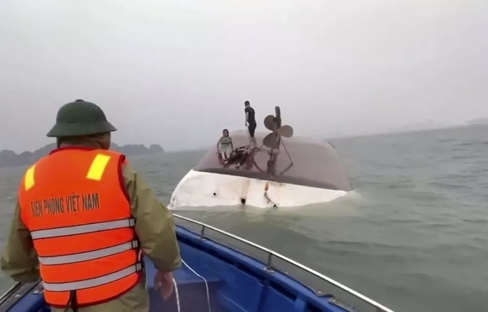 This image from a video provided by QDND shows people on a capsized tourist boat being rescued in Ha Long Bay, Vietnam on Saturday, July 19, 2025. (QDND via AP)