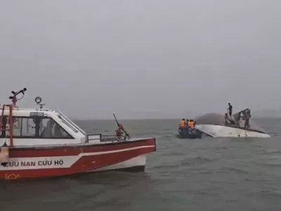 This image from a video provided by QDND shows people on a capsized tourist boat being rescued in Ha Long Bay, Vietnam on Saturday, July 19, 2025. (QDND via AP)