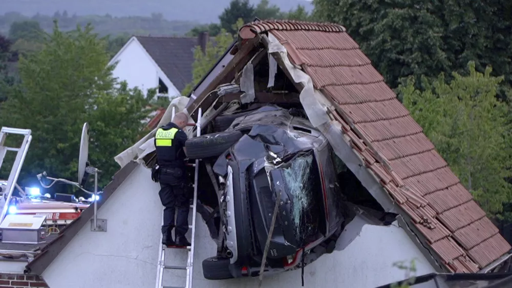 A police officer checks a car stuck in the wall of a barn following an accident in Bohmte, Germany, Sunday, July 20, 2025. (Torben Kipp/Nordwestmedia-TV/dpa via AP)