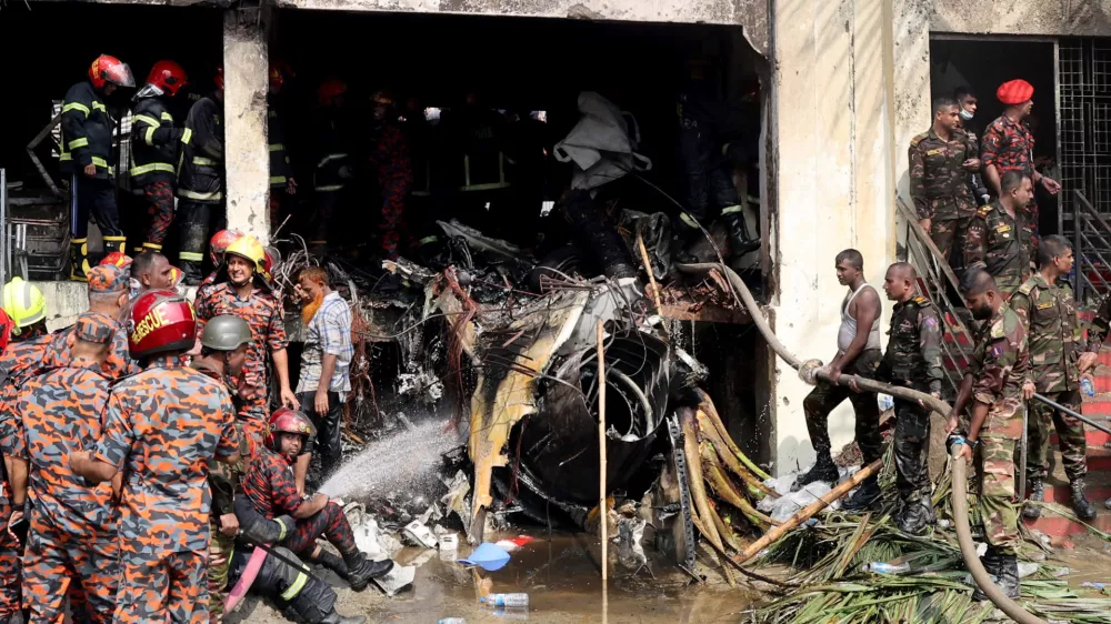 Firefighters and army members work next to the wreckage of an air force training aircraft after it crashed into Milestone College campus, in Dhaka, Bangladesh, July 21, 2025. REUTERS/Stringer