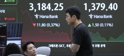 Currency traders work near a screen showing the Korea Composite Stock Price Index (KOSPI) and the foreign exchange rate between U.S. dollar and South Korean won, right, at the foreign exchange dealing room of the Hana Bank headquarters in Seoul, South Korea, Monday, July 28, 2025. (AP Photo/Ahn Young-joon)