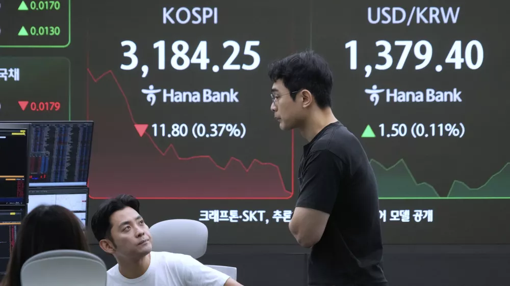 Currency traders work near a screen showing the Korea Composite Stock Price Index (KOSPI) and the foreign exchange rate between U.S. dollar and South Korean won, right, at the foreign exchange dealing room of the Hana Bank headquarters in Seoul, South Korea, Monday, July 28, 2025. (AP Photo/Ahn Young-joon)
