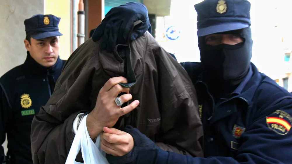 Police lead a man under arrest out of a building in Malaga, Spain, Monday Dec. 19. 2005. Spanish police arrested 14 people Monday on suspicion of recruiting and indoctrinating fighters for Iraq's insurgency. More than 100 police officers staged raids that led to the arrests in the regions of Catalonia and Andalusia as well as in Spain's Balaearic Islands, a police official said. (AP Photo)
