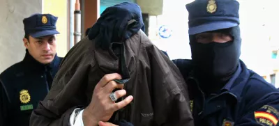 Police lead a man under arrest out of a building in Malaga, Spain, Monday Dec. 19. 2005. Spanish police arrested 14 people Monday on suspicion of recruiting and indoctrinating fighters for Iraq's insurgency. More than 100 police officers staged raids that led to the arrests in the regions of Catalonia and Andalusia as well as in Spain's Balaearic Islands, a police official said. (AP Photo)