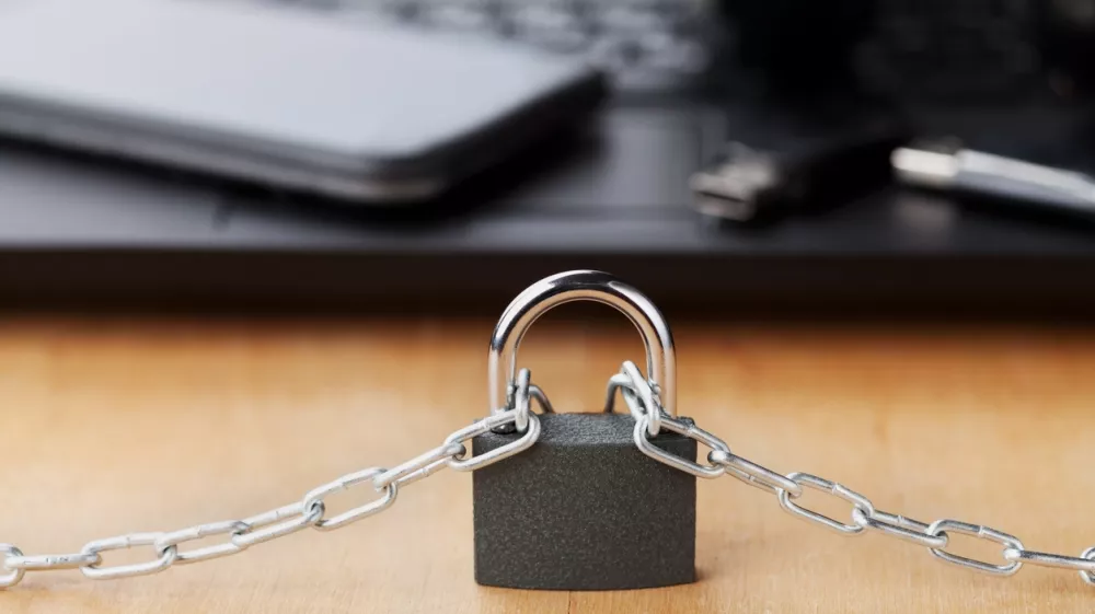 Chain with lock in front of the laptop and smartphone, gadget and digital devices detox concept / Foto: Julia_sudnitskaya