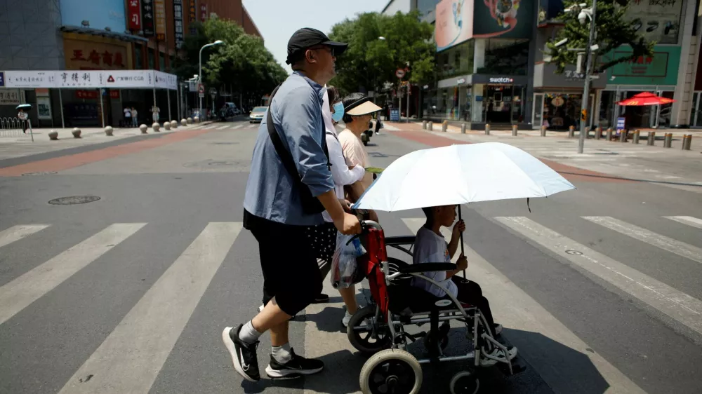 FILE PHOTO: Pedestrians cross a road on a hot day amid an orange alert for heatwave, in Beijing, China June 16, 2023. REUTERS/Florence Lo/File Photo