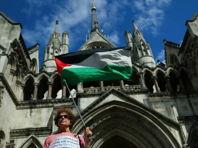 A person holds a Palestinian flag outside the High Court on the day of a hearing about the banned pro-Palestinian campaign organisation Palestine Action, in London, Britain, July 21, 2025. REUTERS/Isabel Infantes