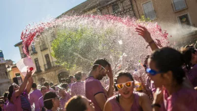 A man pours red wine on revelers during the "Batalla del Vino" (Battle of Wine) in Toro (Zamora), on August 24, 2015. Toro, a small village of Spain known for having Toro wine appellation, celebrated the first battle of wine in the Main Square during the festivities of San Agustin, imitating the wine battle of Haro (La Rioja). Hundreds of people dressed in white cover each other in red wine with water pistols, back-mounted spraying devices, buckets and others. (Photo by Manuel Balles/NurPhoto) (Photo by NurPhoto/NurPhoto via Getty Images)