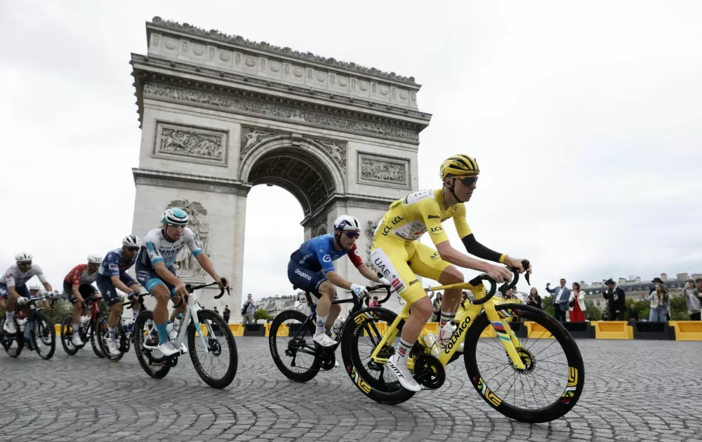 Cycling - Tour de France - Stage 21 - Mantes-la-Ville to Paris - Paris, France - July 27, 2025 UAE Team Emirates XRG's Tadej Pogacar wearing the yellow jersey in action with riders as they pass the Arc de Triomphe during Stage 21 REUTERS/Benoit Tessier