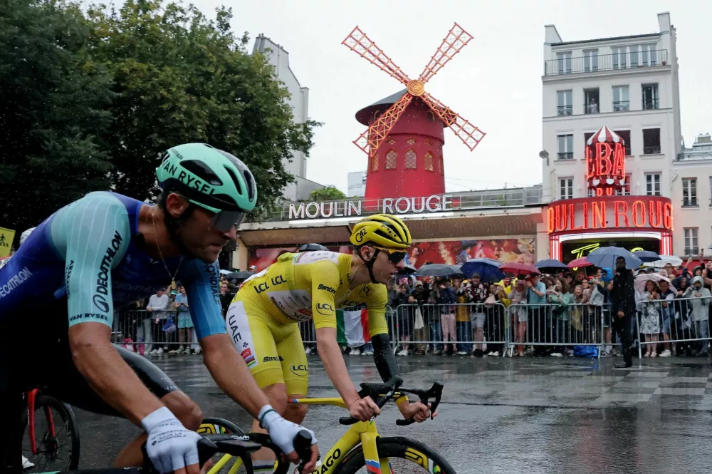 Cycling - Tour de France - Stage 21 - Mantes-la-Ville to Paris - Paris, France - July 27, 2025 UAE Team Emirates XRG's Tadej Pogacar wearing the yellow jersey in action with riders as they pass The Moulin Rouge during Stage 21 REUTERS/Christian Hartmann