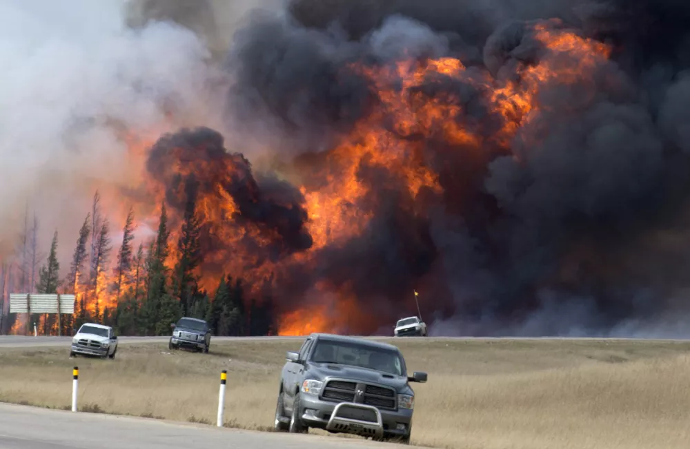 A wildfire burns south of Fort McMurray, Alberta, near Highway 63 on Saturday, May 7, 2016. Canadian officials hoped to complete the mass evacuation of work camps north of Alberta's main oil sands city of Fort McMurray on Saturday, fearing the growing wildfire could double in size and reach a major oil sands mine and even the neighboring province of Saskatchewan. (Jonathan Hayward /The Canadian Press via AP) MANDATORY CREDIT
