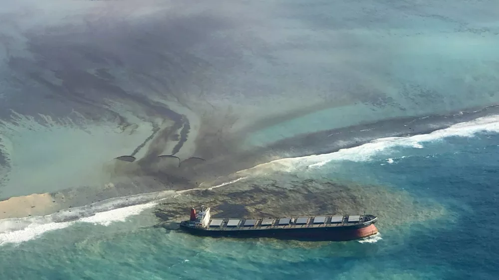 This photo taken and provided by Eric Villars shows oil leaking from the MV Wakashio, a bulk carrier ship that recently ran aground off the southeast coast of Mauritius, Friday, Aug. 7, 2020. Anxious residents of the Indian Ocean island nation of Mauritius are stuffing fabric sacks with sugar cane leaves to create makeshift oil spill barriers as tons of fuel leak from a grounded ship. The government has declared an environmental emergency and France says it is sending help from its nearby Reunion island. (Eric Villars via AP)