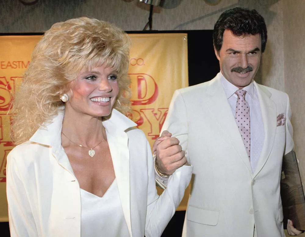 FILE - Burt Reynolds, right, holds hands with Loni Anderson at a luncheon, March 27, 1987, in Los Angeles. (AP Photo/Bob Galbraith, File)
