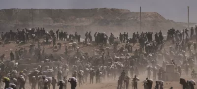 Palestinians carry humanitarian aid packages near a Gaza Humanitarian Foundation distribution center operated by the U.S.-backed organization, in Netzarim, central Gaza Strip, Monday, Aug. 4, 2025. (AP Photo/Abdel Kareem Hana)